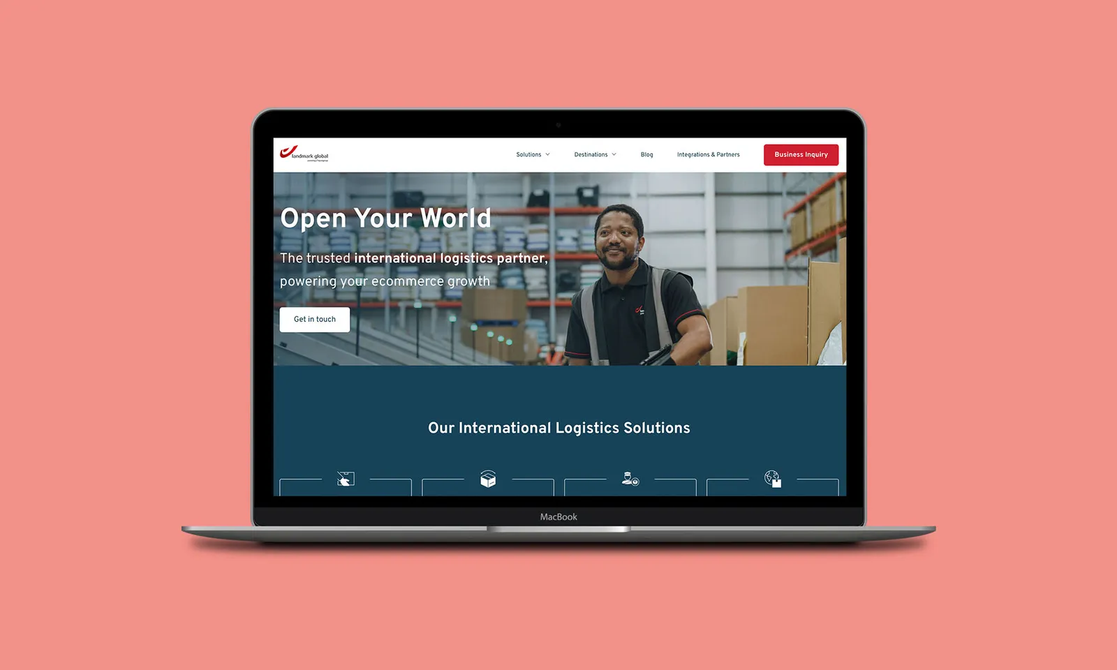 A laptop displays a logistics company website featuring a warehouse employee with boxes, navigation menu, and call-to-action buttons, set against a solid coral background.