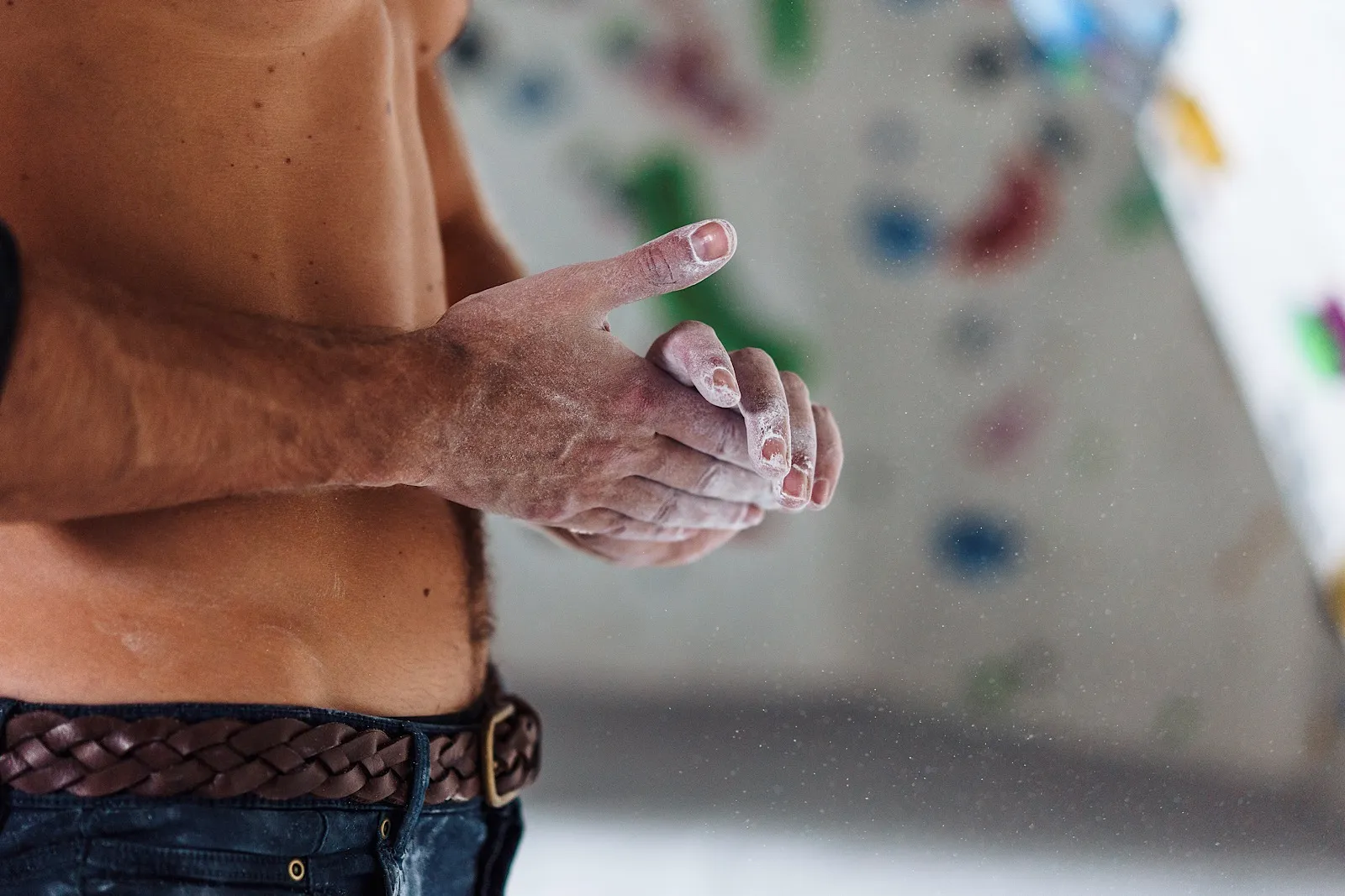 Topless Man rubbing chalk on hands in rock climbing centre