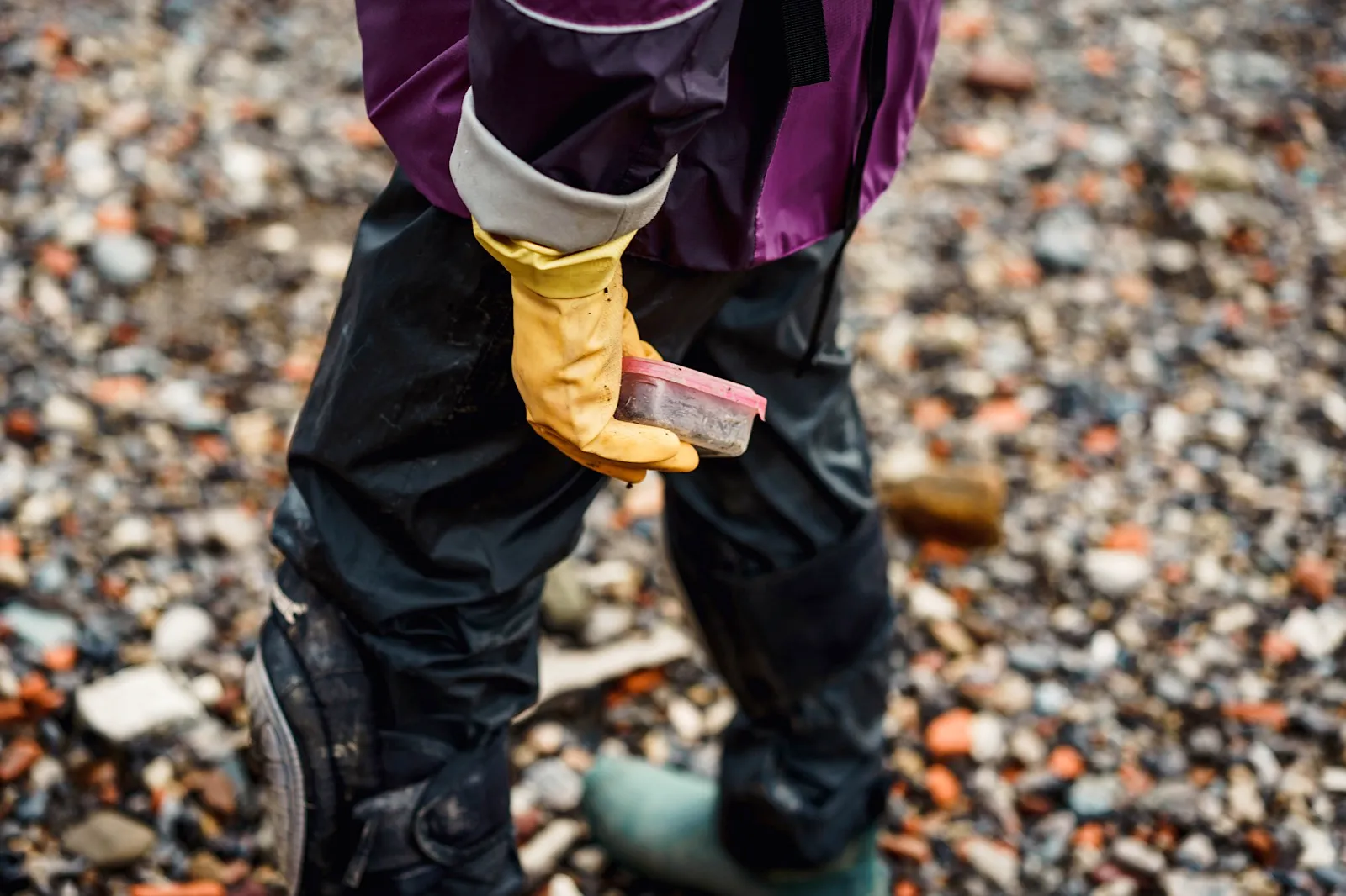 Image of mudlarker holding a find in their rubber gloves