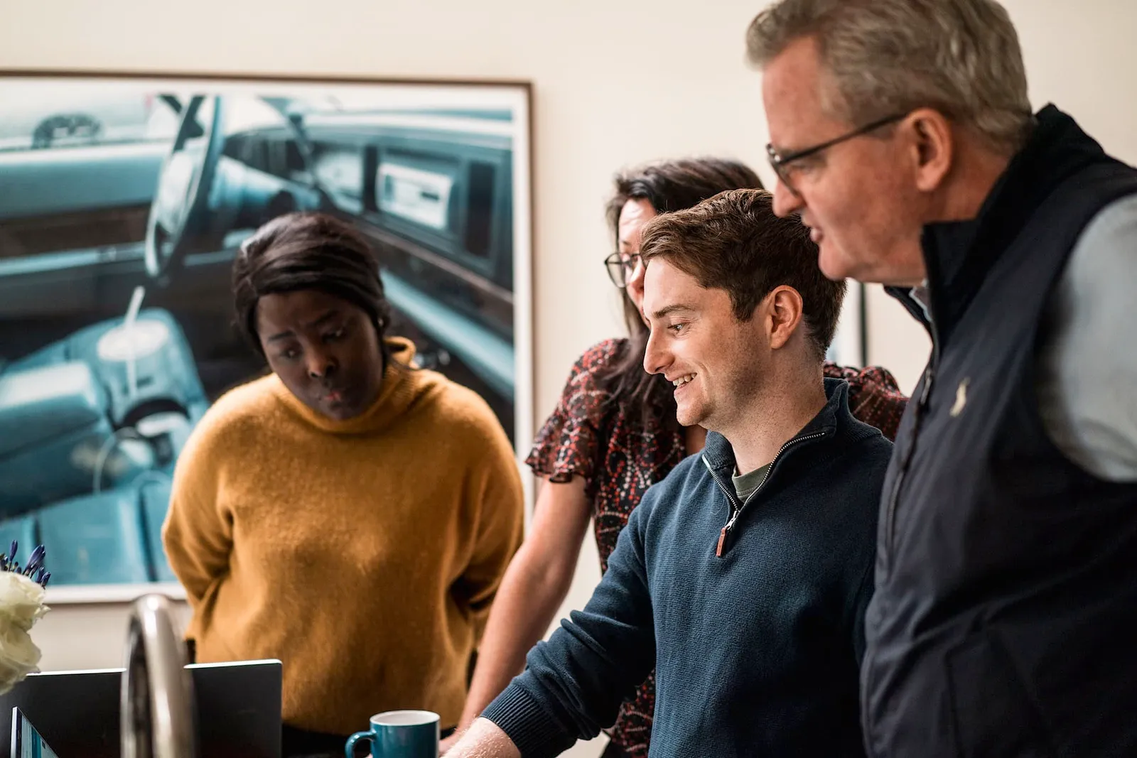 group of people working around a laptop in a natural setting.