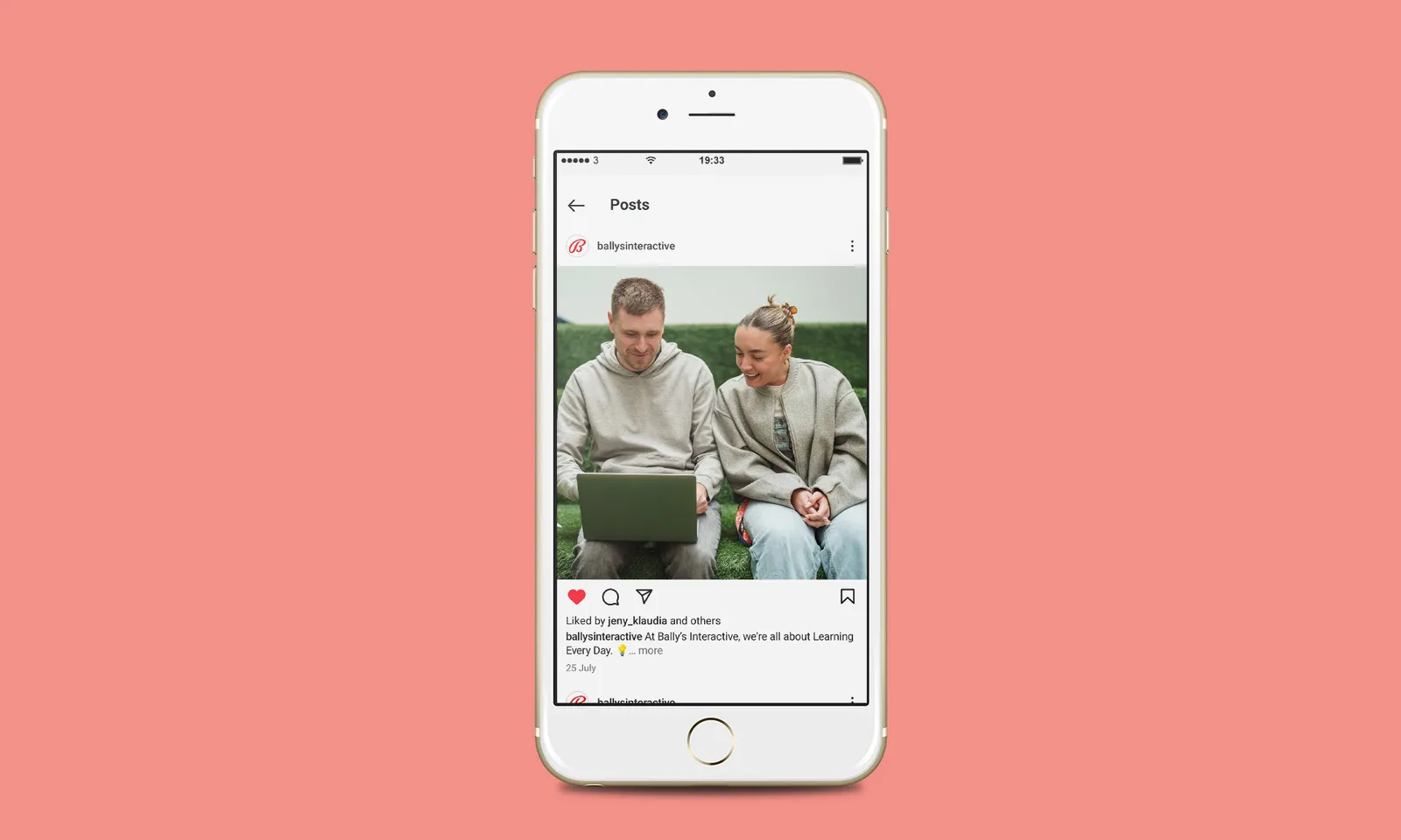 Smartphone displaying a social media post of two people sitting on a sofa, one using a laptop.