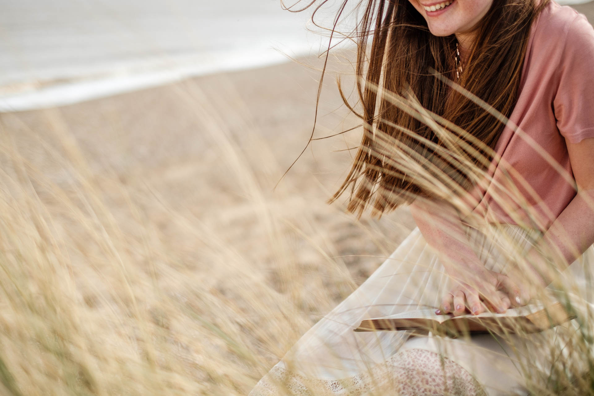 Girl smiling reading a book on the beach