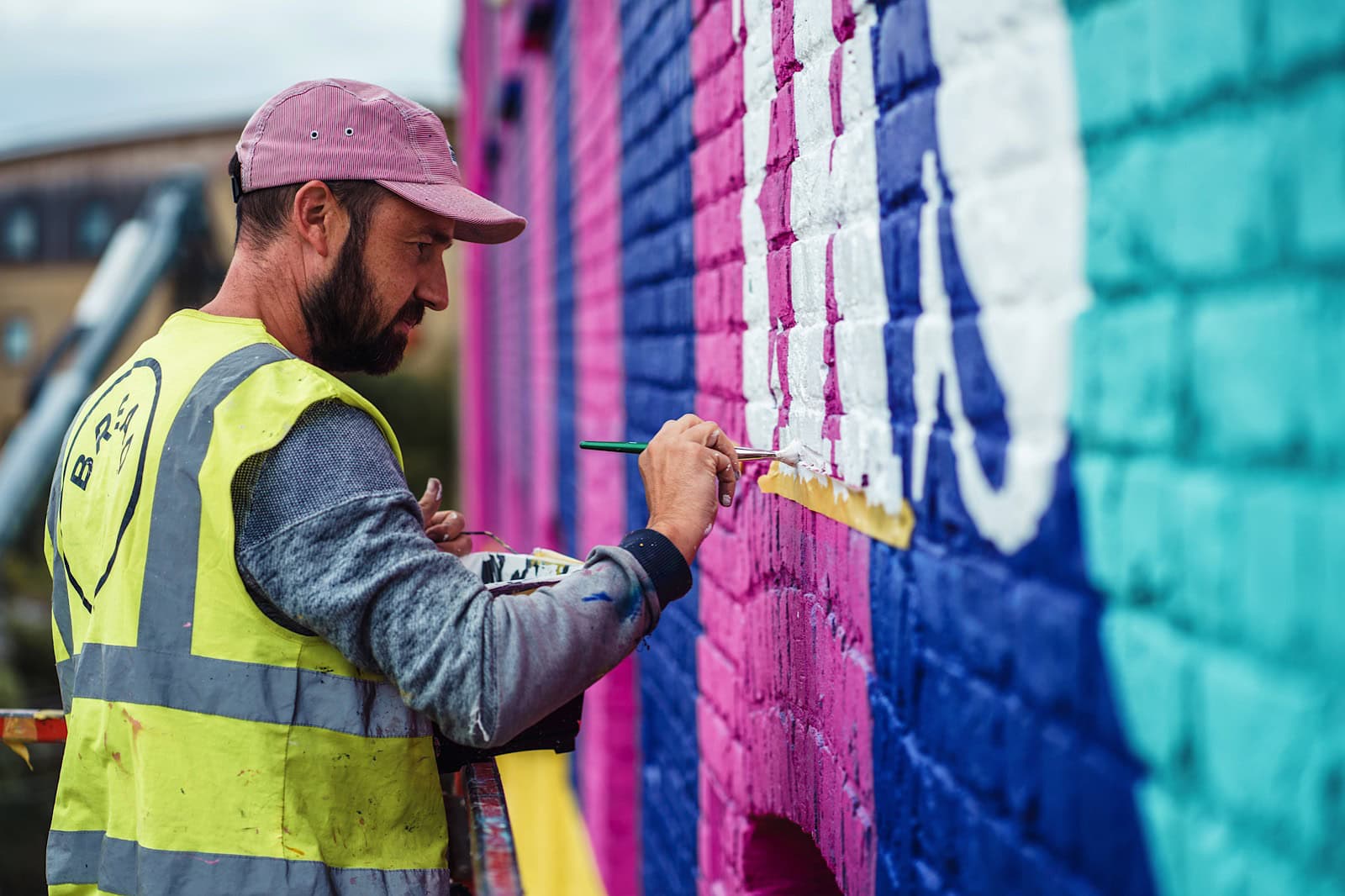 Commercial portrait of a man painting a mural on the side of a building