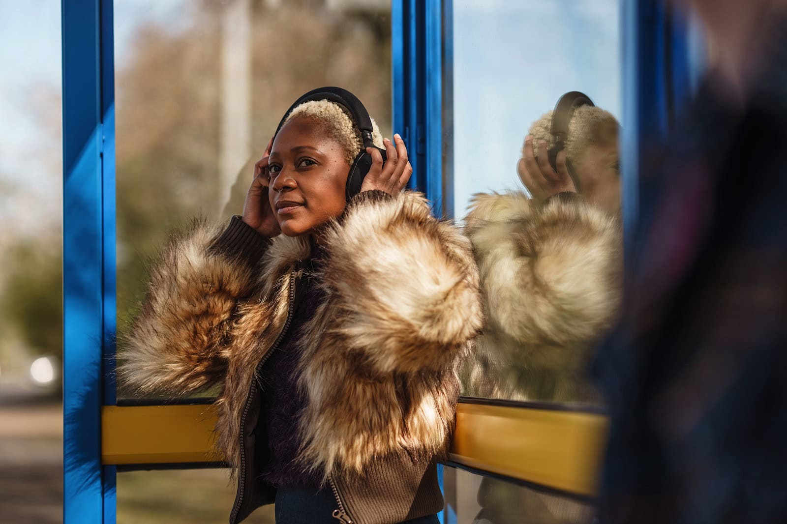 Woman stood at bus stop adjusting headphones