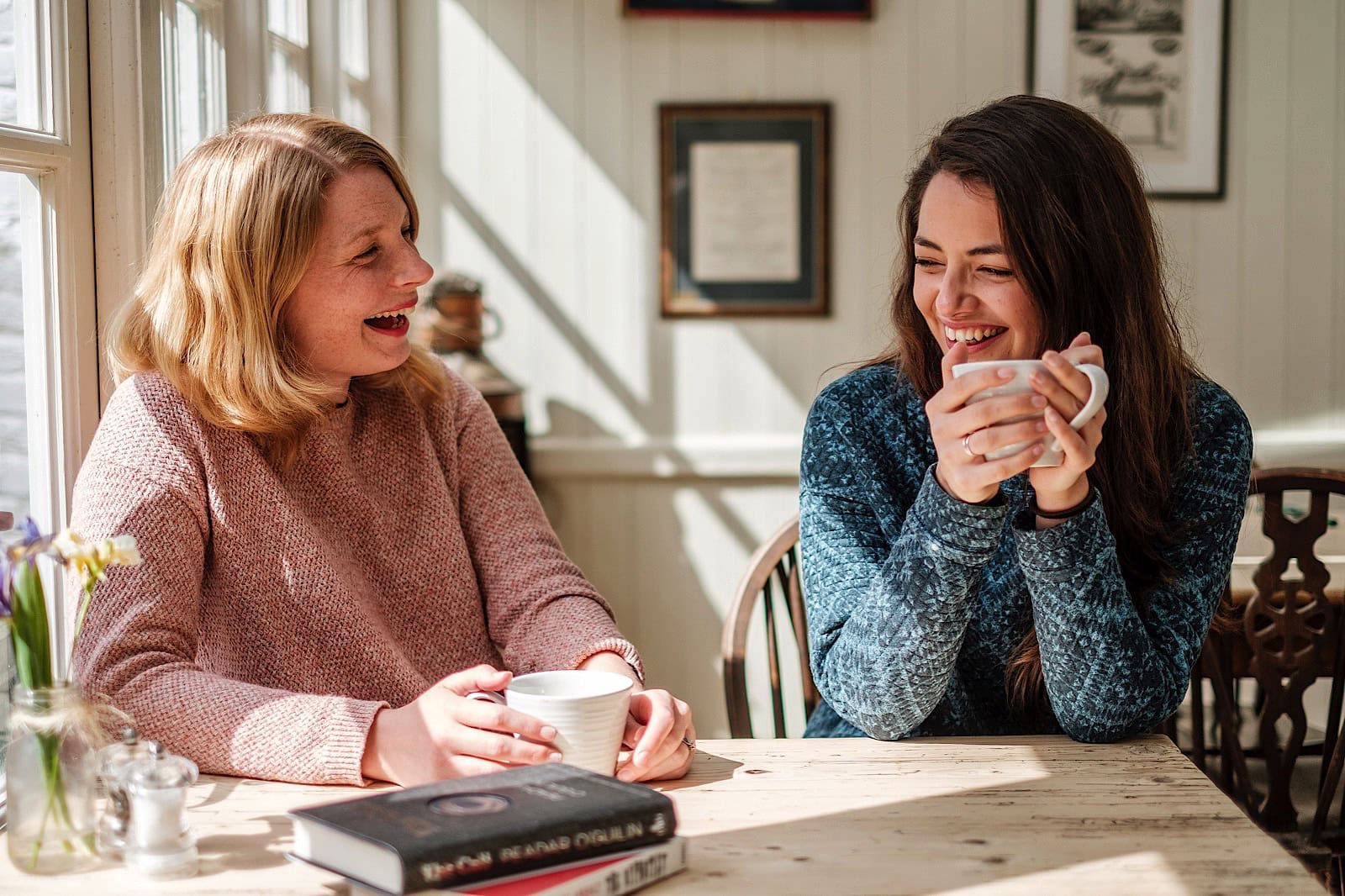 2 women laughing whilst drinking coffee