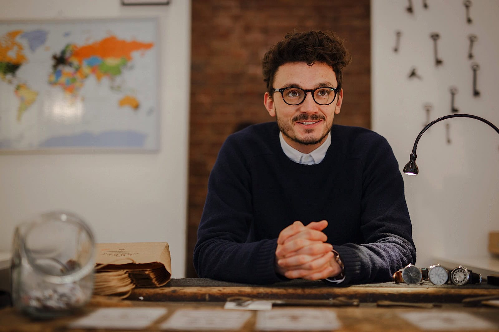 commercial portrait of man sat at a workbench with watches and packaging