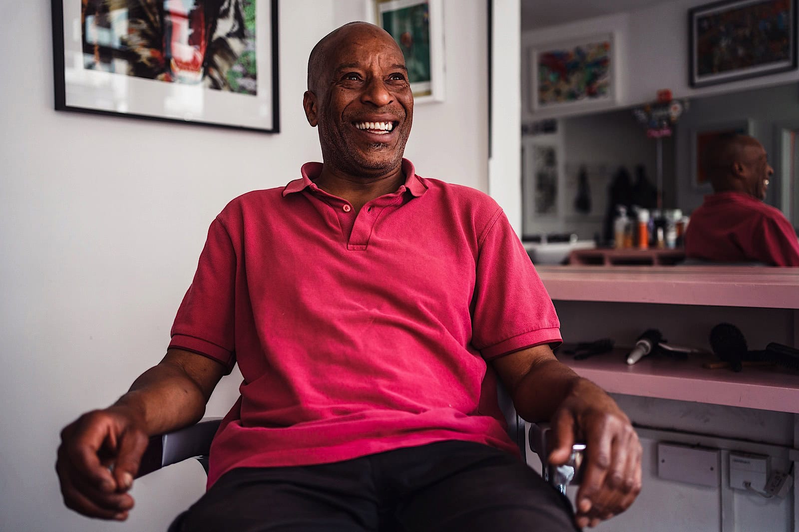 Photograph of a man wearing a pink t-shirt, smiling.