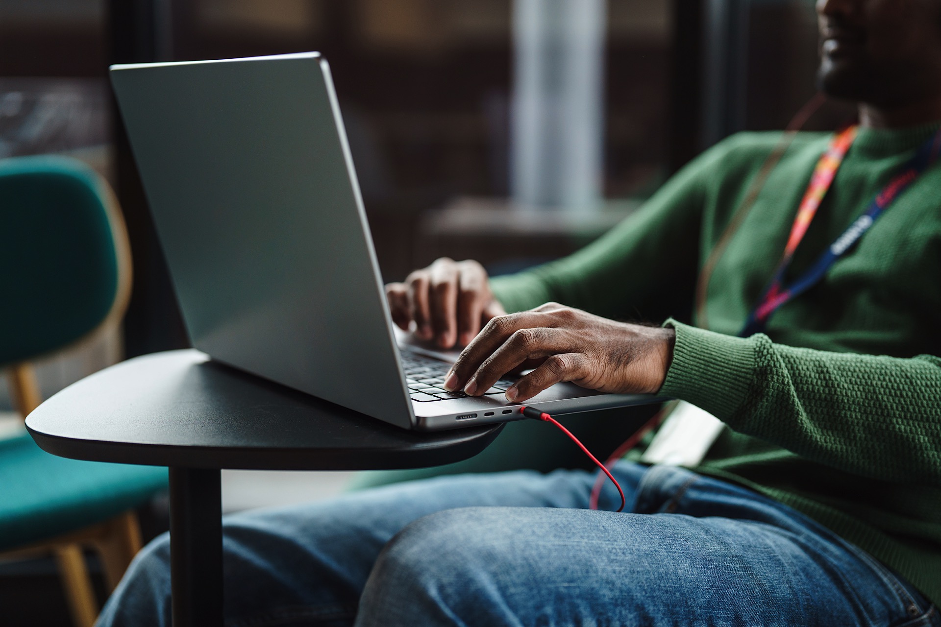 Man in green jumper sat typing at his computer