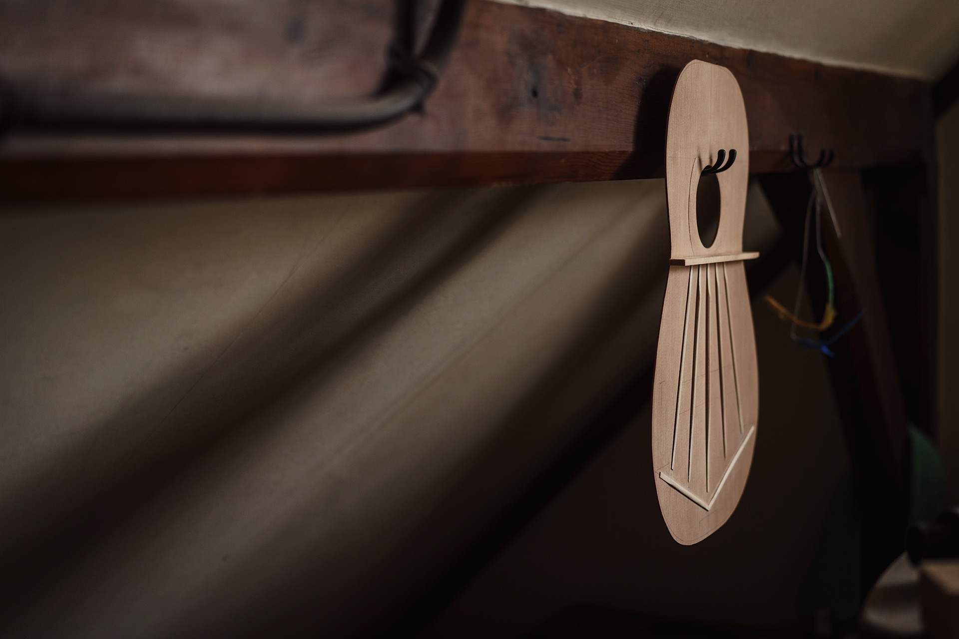 Guitar body piece hangs on a slanted attic wall.