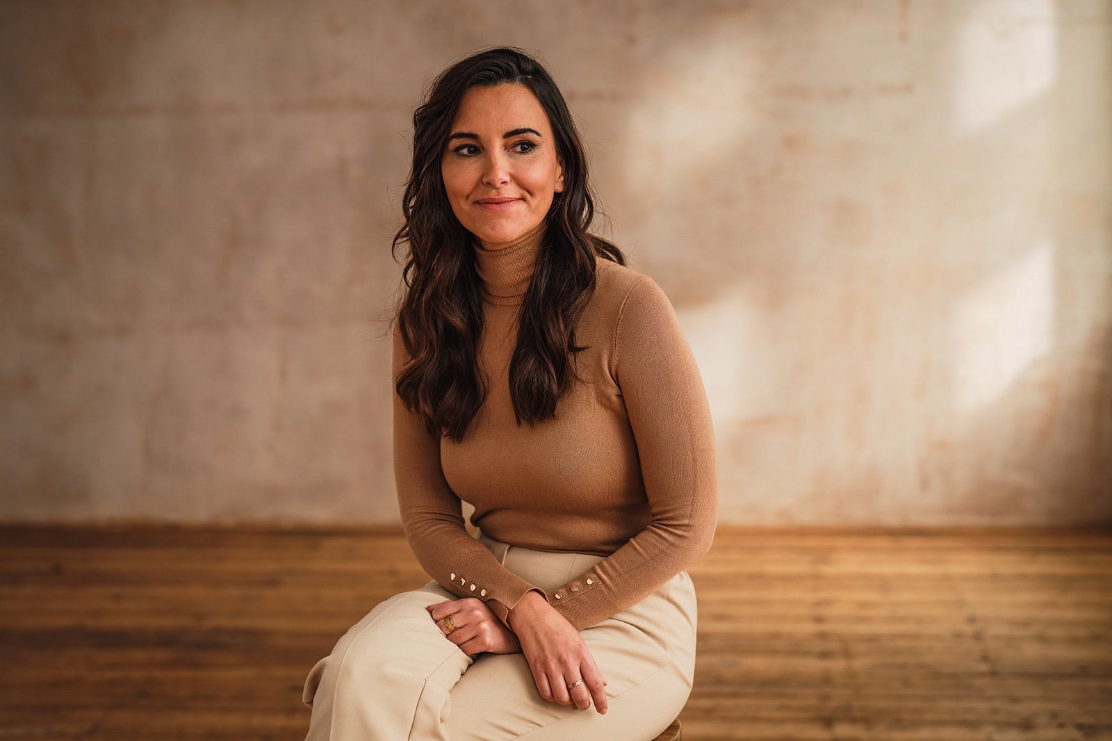 Woman sat on stool smiling during commercial portrait shoot for Unmind