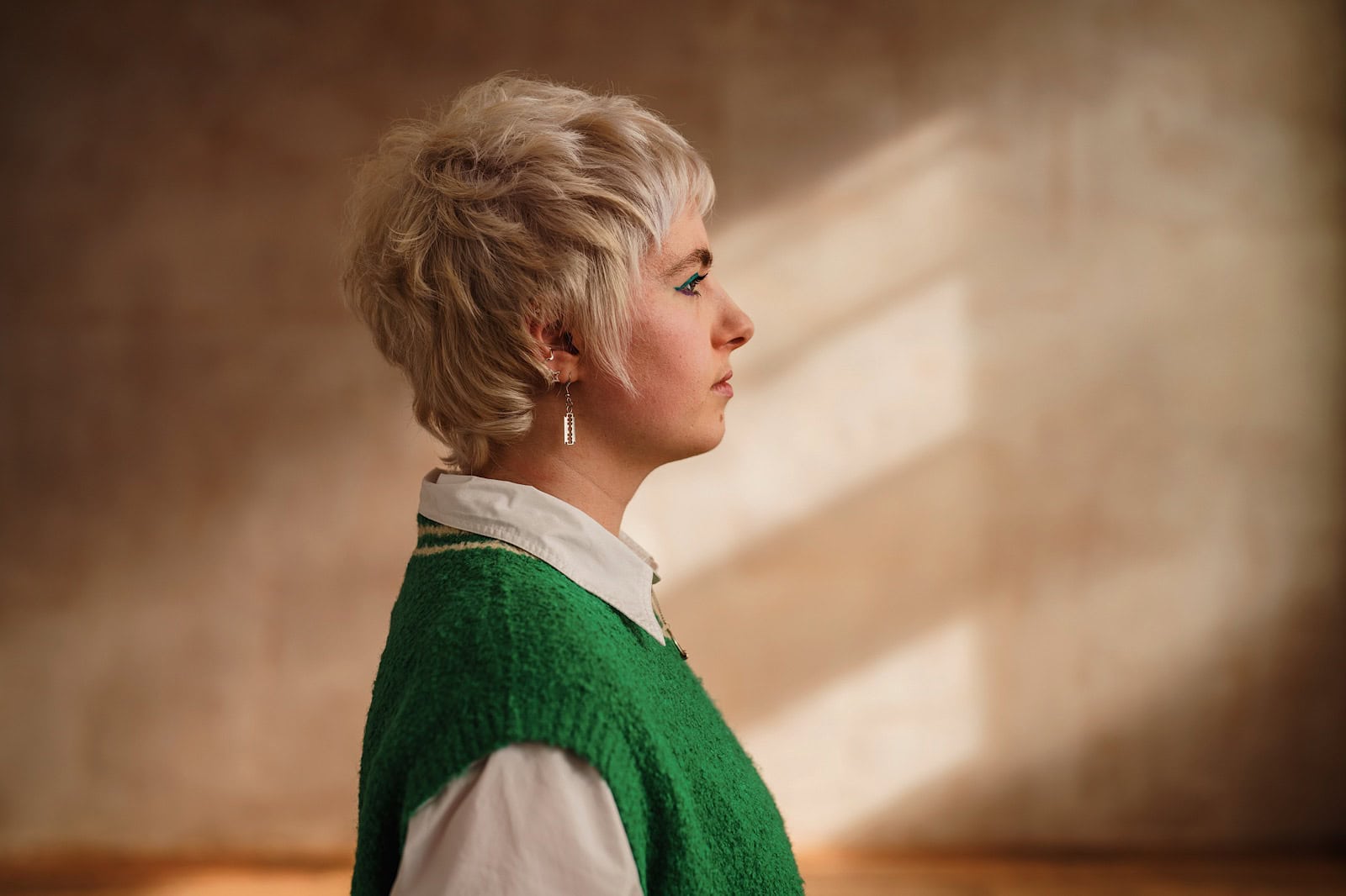 Studio portrait of a woman wearing a green jumper side on